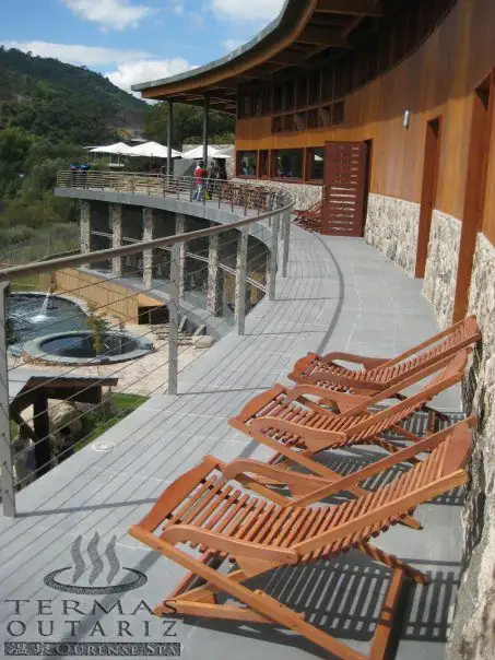 Terraza de madera con tumbonas sobre las piscinas exteriores de Termas Outariz